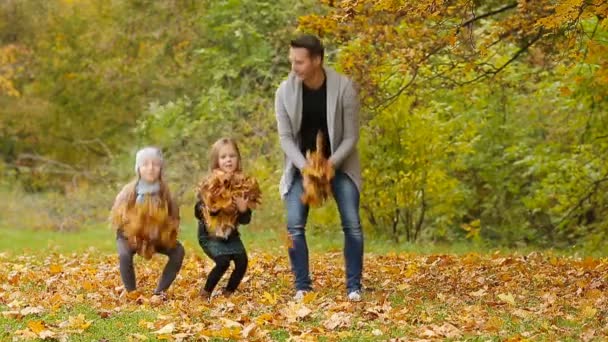 Mladý, usměvavý rodina baví a házel listí kolem na podzimní den venku - Záběry, video