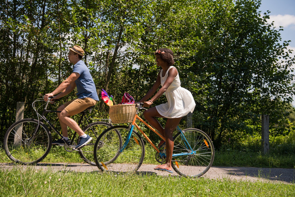 Young multiethnic couple having a bike ride in nature - Фото, изображение