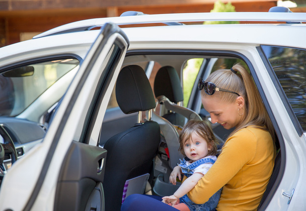 Giovane donna con sguardo sorpreso uscire dalla macchina con il bambino
 - Foto, immagini