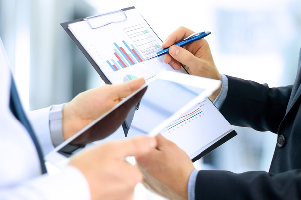 Compañeros de negocios trabajando y analizando cifras financieras en una tableta digital
 - Foto, imagen