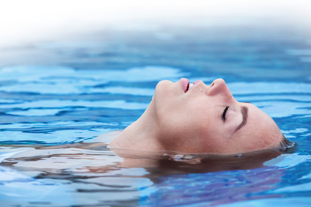Woman floating in pool - Photo, image