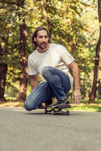 Skateboarder squatting on a skateboard and ride through the fore - Photo, image