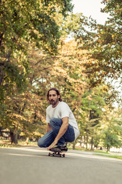 Skateboarder squatting on a skateboard and ride through the fore - Photo, image