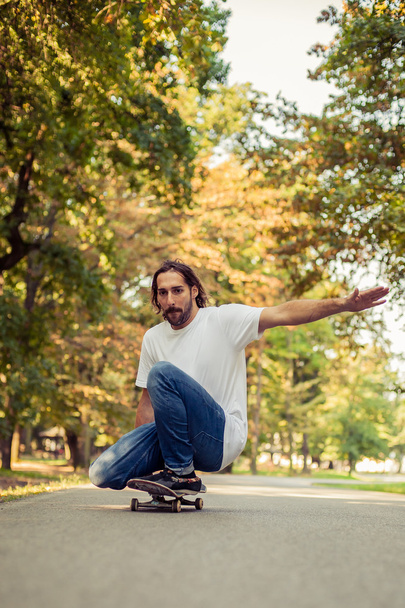 Skateboarder squatting on a skateboard and ride through the fore - 写真・画像
