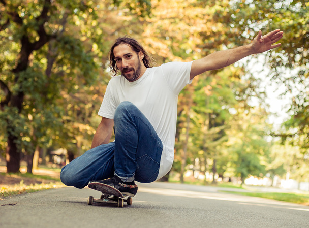 Skateboarder squatting on a skateboard and ride through the fore - Photo, Image