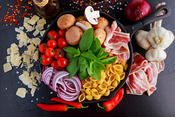 Pannulla pasta pekonilla, kastanjasienillä, kirsikkatomaateilla, punasipulilla, conchigliella ja basilikan lehdillä
 - Valokuva, kuva