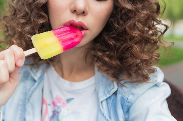 beautiful girl with curly with a naked sexy lips eating color ice cream in a cafe in the park a bright summer day - 写真・画像