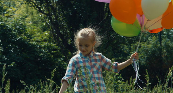 Preschooler girl walking with balloons and in the park - Video, Çekim