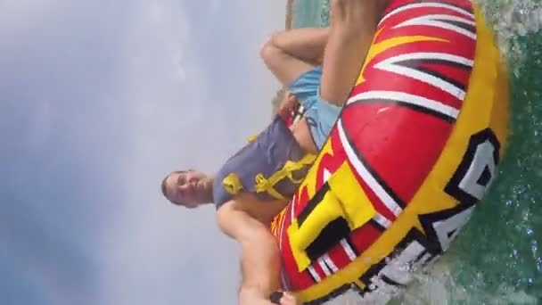 Man sitting in inflatable ring towed by a boat in the water and recording himself with Go Pro camera - Footage, Video