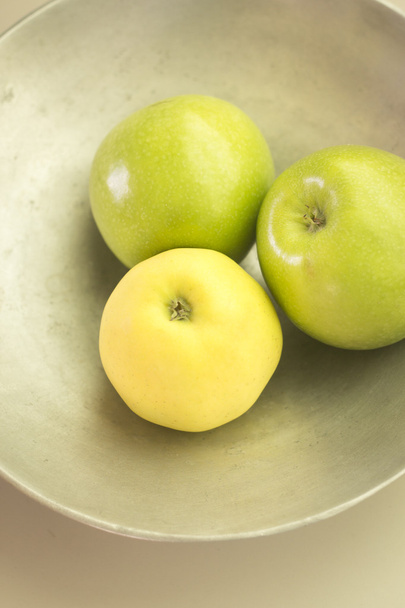 Kolme vihreää omenaa lautasella
 - Valokuva, kuva