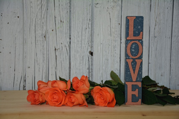 Blöcke mit Liebe Schriftzug hoch gestapelt, mit orangen Rosen - Foto, Bild