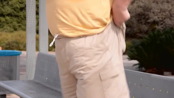 Hombre de pie tira hacia arriba cayendo pantalones beige
 - Metraje, vídeo