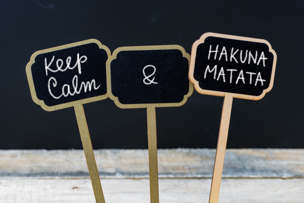 Mantenga la calma y el mensaje de Hakuna Matata escrito con tiza en las etiquetas de la mini pizarra
 - Foto, imagen