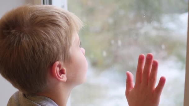 dítě se dívá z okna na sníh - Záběry, video