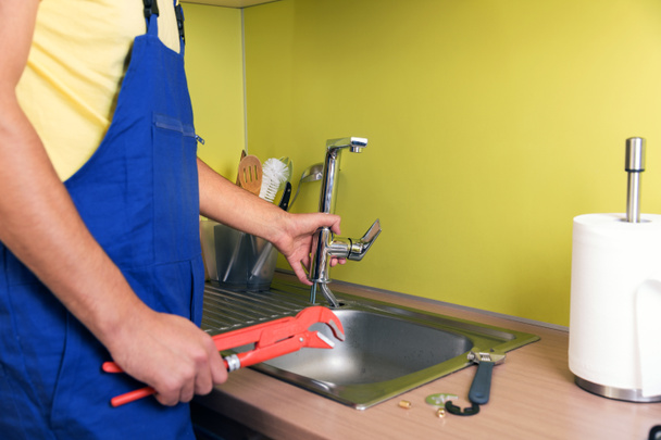 plumber working in domestic kitchen, repairing faucet - Fotoğraf, Görsel