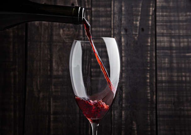 Gieten van rode wijn in het glas uit fles  - Foto, afbeelding