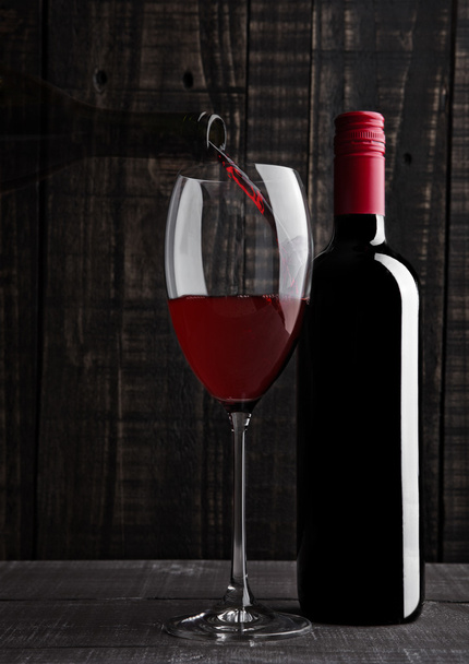 Pouring red wine into the glass from bottle  - Foto, imagen