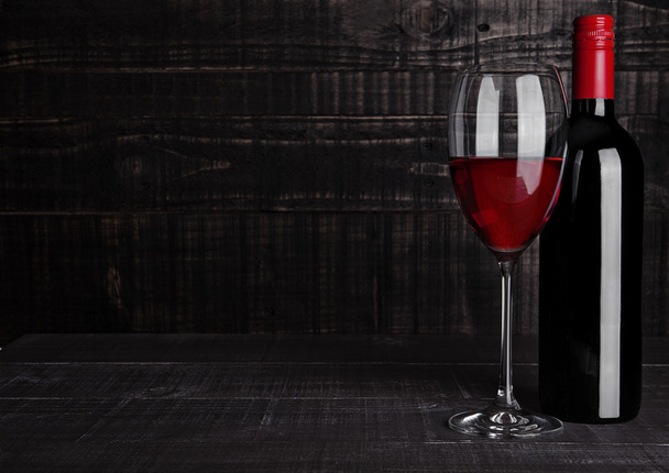 Пляшка і келих червоного вина на дерев'яному фоні
 - Фото, зображення