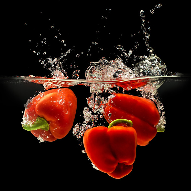 Group of bell pepper falling in water on black - Foto, immagini