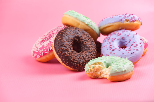 Солодкі барвисті смачні пончики на рожевому фоні
.   - Фото, зображення