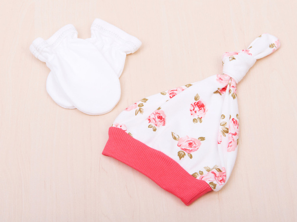 Baby goods. Children's clothing, hat with flowers and white gloves on the background of the changing table. - Fotoğraf, Görsel
