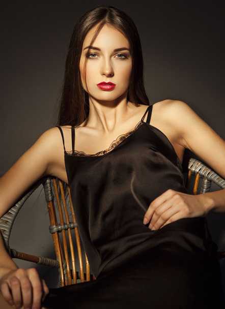 Luxury elegant woman in lace silk black dress sitting over dark  - Фото, изображение