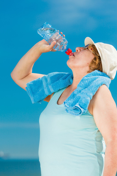 old woman drinking mineral water in plastic bottle outdoor - Zdjęcie, obraz