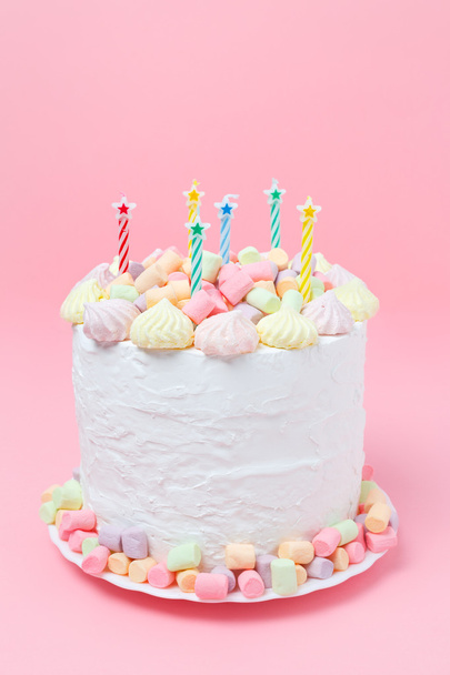 Holiday homemade cake decorated with marshmallow, meringue, candy and candles on a pastel pink background. Birthday cake - Foto, Bild