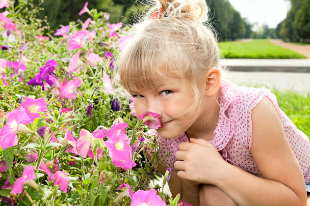 Little girl enjoys the smell of flowers - Fotoğraf, Görsel