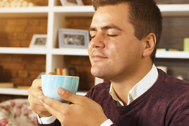 Jonge man drink koffie, thee of chocolademelk - Foto, afbeelding