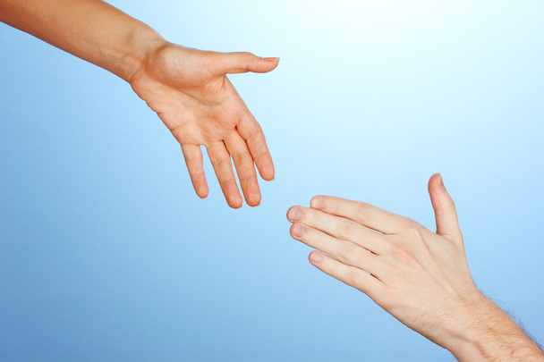 Women's hand goes to the man's hand on blue background - Zdjęcie, obraz