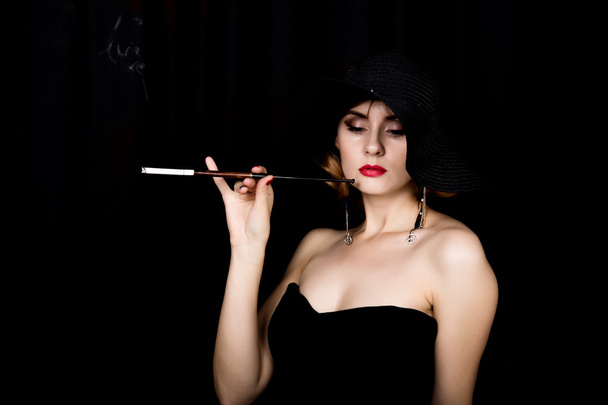 Beauty retro female model with professional makeup and mouthpiece in hand. fashion vintage woman on a dark background - 写真・画像
