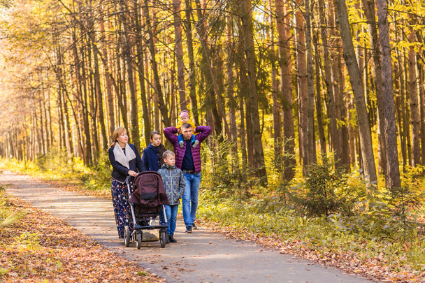 Happy young family walking down the road outside in autumn nature. - 写真・画像