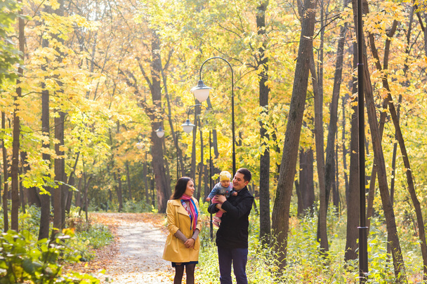Onnellinen nuori perhe kävelee kadulla syksyllä luonto
. - Valokuva, kuva