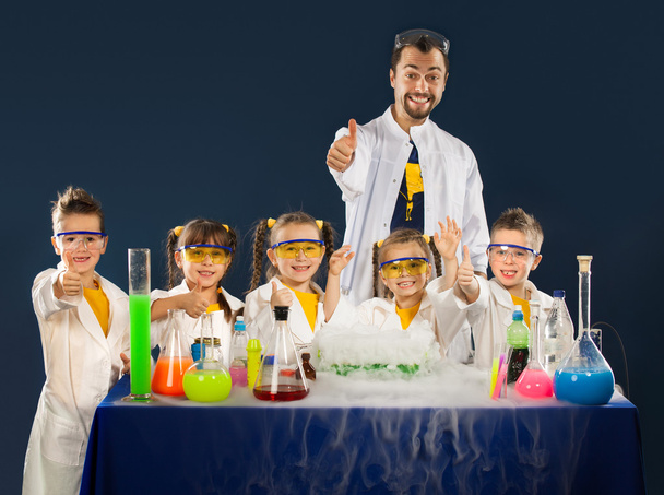 Onnelliset lapset tiedemiehen kanssa tekemässä kokeita laboratoriossa
 - Valokuva, kuva
