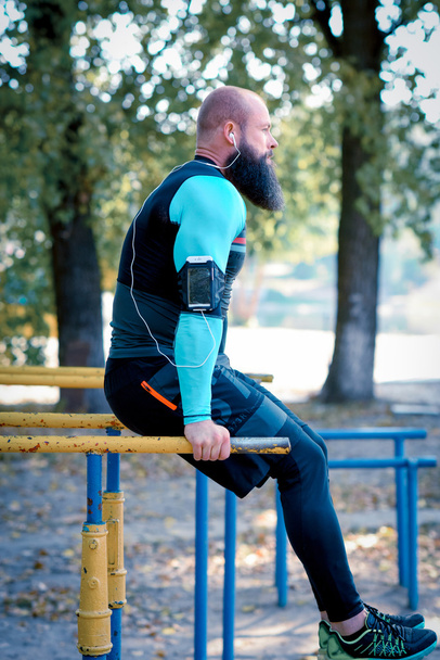 Homem barbudo muscular em barras paralelas
 - Foto, Imagem
