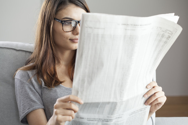 Young woman reading newspaper - Фото, изображение