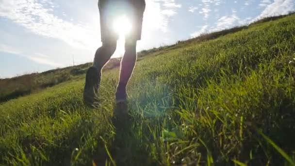 Mladý muž přejel zelený kopec na pozadí modré oblohy. Sportovec je běhat v přírodě při západu slunce. Sportovní běžce běhat do kopce venkovní za úsvitu s hrdlem. Běžecké školení. Zpomalený pohyb - Záběry, video