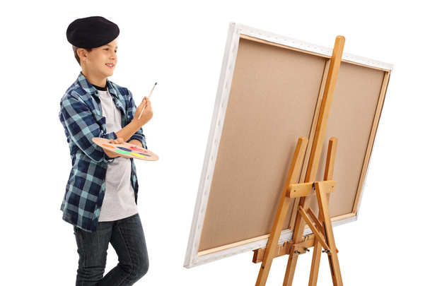 Boy looking at canvas with paintbrush and palette - Fotografie, Obrázek