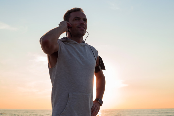 Człowiek po uruchomieniu na plaży stojące w zachód słońca  - Zdjęcie, obraz