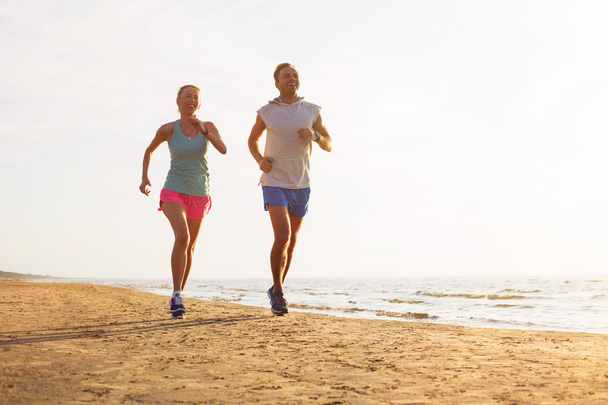 Feliz casal fitness correndo na praia
 - Foto, Imagem