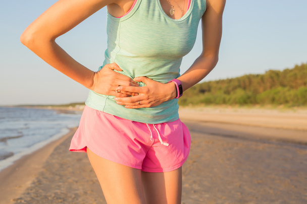 Mujer corredora con calambres estomacales
 - Foto, Imagen