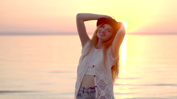 Mujer rubia bonita en sombrero disfrutando de vacaciones de verano en el océano puesta de sol de oro
 - Metraje, vídeo