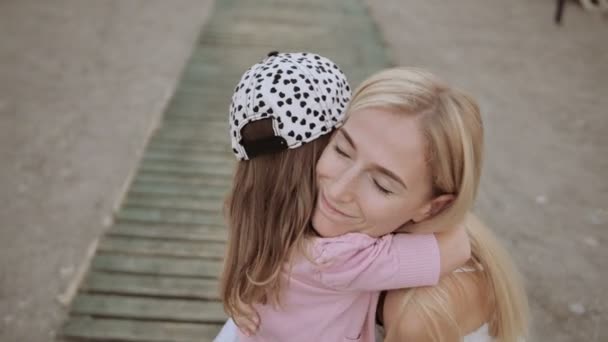 молода мати зі своєю маленькою дочкою цілується на причалі біля моря
 - Кадри, відео