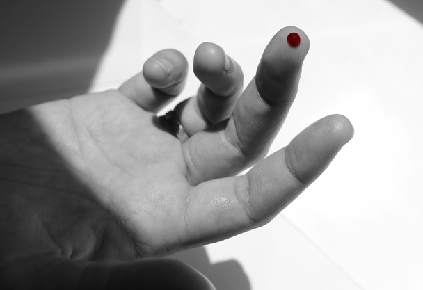 A black and white finger with red blood drop - Photo, image