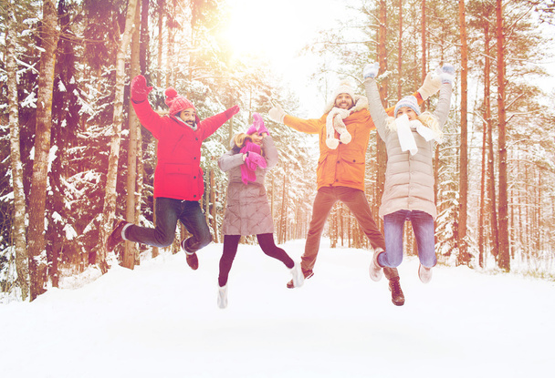 group of smiling men and women in winter forest - Foto, Bild