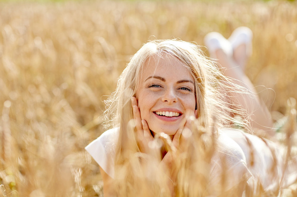 happy woman or teen girl lying in cereal field - Zdjęcie, obraz