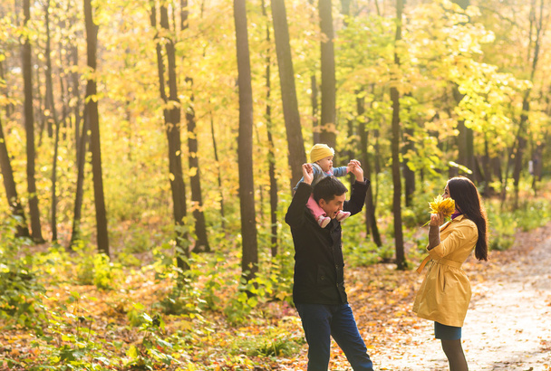 mladá rodina s jejich dcerou tráví čas venkovní v podzimním parku - Fotografie, Obrázek