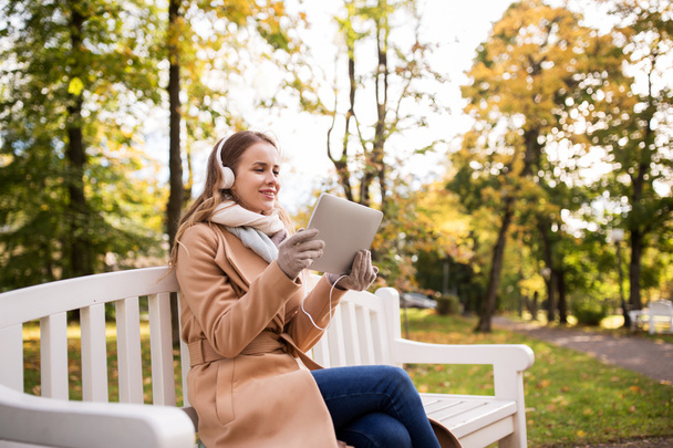 woman with tablet pc and headphones in autumn park - Fotó, kép