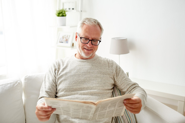 senior man in glasses reading newspaper at home - Foto, afbeelding